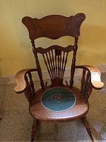 Full view of vintage wooden rocking chair with carved wood and needlepoint seat.