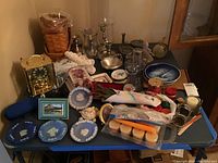 Overview photo of entire lot showing all items including baskets, plates, candlesticks, clock, candles, and coasters