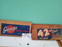 Photo showing both wood slab melon advertising signs side by side, illustrating overall size and condition.