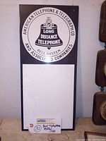 Full view of the metal advertising sign on a wall showing design and size context with a mounting tag below