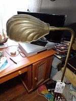 Close-up side view of the scalloped shell-shaped brass shade on the floor lamp.