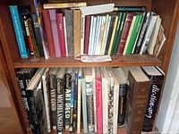 Two shelves of books with assorted titles including art, poetry, travel and dictionary.