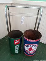 Photo showing the 7up and Boston Red Sox metal barrels side by side placed inside a chrome rack.