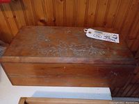 Full view of the rectangular wooden box with a hinged top showing carved elephant and floral designs on the lid.