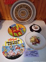 Overview photo showing all six collectible plates arranged on a table against wood panel backdrop, clearly displaying different designs and sizes.