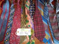 Photo shows 11 men's ties laid out side-by-side displaying various colors and patterns including stripes, floral, geometric, and plaid.