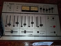 Top view showing front panel with Numark branding, two VU meters, multiple sliders for channels and graphic equalizer controls, power and headphone jacks.