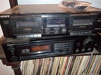 Sony dual cassette stereo deck on top of Onkyo receiver, showing front panel controls and tape slots
