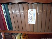 Shelf with a row of brown leather-like hard cover volumes of The Watchtower from various years such as 1963, 1971, 1983, 1996, 1999, 2012, 2015. Books have embossed titles and are in good condition for age.