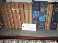 Photo of vintage hardcover volumes of The Watchtower Bible with brown and dark blue covers, some labeled with years '59 and '67.