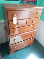 Front view of the vintage maple bureau showing five drawers and wooden knob handles, in good aged condition.