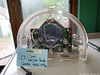 Clear front view showing entire radio interior, control knobs, and circular dial with frequency markings. Tag visible with model and lot number information.