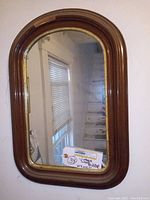 Full view of vintage hallway mirror with arched top wood frame showing the reflective glass and wood molding details.
