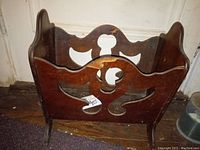 Front-side angled view showing the carved side panels and overall structure of the wooden magazine rack.