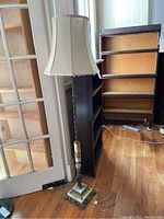Full vertical view of the antique marble and brass floor lamp next to a door and bookshelves, showing its overall height and base design