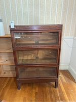 Front view of three-tier barrister bookcase showing oak frame, glass doors and brass hardware