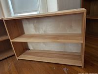 Front and side angle view of the two tier pine bookcase showing both shelves and its overall condition.