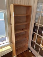 Full front view of six-tier pine bookshelf showing all shelves and storage space, placed indoors.
