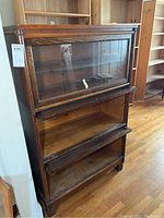 Front view of the Weis barrister bookcase showing the four tiers with glass doors, one door missing knob, sliders on two lower doors with visible damage