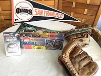 Photo showing entire lot including sealed 1994 Topps box, Don Mattingly baseball in packaging, two mitts, and two pennants (San Francisco Giants and Oakland Athletics)