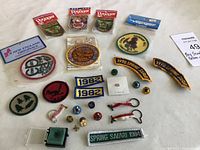 Wide shot of vintage Boy Scouts of America patches and pins, including year patches from 1982, 1978 Spring Camp patches, event patch for Spring Safari 1984, various round patches, and small pins.