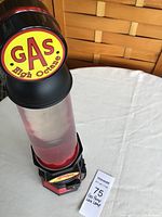 Full view of lava lamp on white cloth showing gas pump styled base and cylinder with pink wax inside