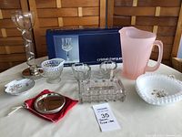 Lot contents showing Cristal d'Arque boxed glasses, frosted pink pitcher, glass coasters, serving spoon holders, creamer, decorative bowls, glass box with chip in lid, and trinket dish.