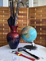 Overall view of lot showing globe light, red and blue glaze vase holding umbrellas, walking sticks, Mickey Mouse back scratcher, and shillelagh walking stick