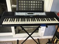 Full view of Yamaha black PSR-E213 keyboard on stand, showing keys and control panel.