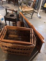 Wide view showing bamboo sling lounge chair, wooden plant stand, several nested bamboo baskets, plaster deer head, and additional furniture.