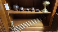 Five brass bells arranged on a wooden shelf with brass train shelf and hanging shelf below