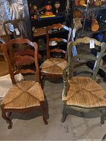 Three wooden ladder back chairs with woven wicker seats; two natural wood finish, one distressed green painted finish, visible wear, nicks and scratches.