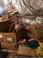 Boxes containing assorted holiday decorations including large wooden signs shaped like ice skates and directional signs for skating pond, warming house, hot cocoa. Wooden flower stakes with painted hearts and leaves.