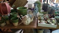 Overview photo of the lot showing various planters, a ceramic teapot, glassware, succulents, and the snow globe.
