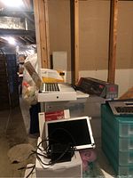 Overview of MacBook Air laptop, keyboard panel, external dock and some hard drives stacked on boxes