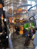 Metal storage rack with five adjustable wire mesh shelves, shown with various decorative items and a broom, located in basement with foil insulated walls