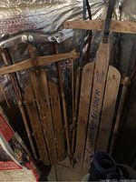 Photo showing two vintage wooden sleds stacked, one labeled 'Lightning Guider'.