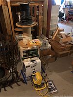 View of spools of wire stacked vertically with boxes around and portable yellow light on floor