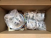 Packed box showing wrapped tea cups and stacked plates with bubble wrap for protection.