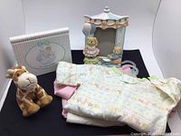 Lot overview showing baby clothes, stuffed giraffe, picture frame, and photo album