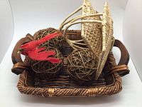 Large square wicker basket filled with decorative items: two wicker spheres and red artificial feathers