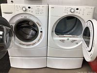 Front view of washer and dryer on pedestals with doors open