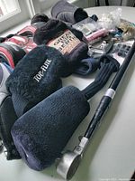 Golf accessories including multiple golf club headcovers, golf putter, and golf bags seen on a white surface