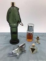 Photo showing green Avon horse-shaped perfume bottle, clear cylindrical Calvin Klein Escape bottle, clear star-shaped Angel by Thierry Mugler bottle, small ornate gold-tone bottle, and bubble blower necklace.