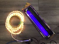 Photo of 12-foot warm white rope lighting coiled and an 18-inch blacklight tube in holder with packaging, both plugged for use.