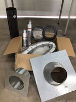 Box with various venting accessories including stainless steel pipes, flexible pipe, collars, and flashing plates.