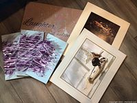 Multiple art pieces laid on floor showing variety of prints and canvas pieces including framed work and triptych canvas set with nautical theme.