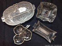 Four vintage glass serving dishes arranged together on black background showing variety in shape and design.