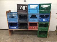 Photo of wooden storage rack measuring approx. 54 x 13.5 x 46 inches, filled with multiple colored plastic crates in green, blue, black, brown, and red, labeled with brands Mont Blanc and Saltlex.