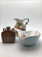 Front view of the three vintage items: hand painted fruit jug, brown mini vase, blue gravy bowl.